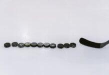 A row of hockey pucks and a stick on an ice rink, perfect for sports content.