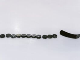 A row of hockey pucks and a stick on an ice rink, perfect for sports content.