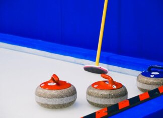 Квебек и Саскачеван вышли в финал плей-офф чемпионата Канады по кёрлингу на колясках Curling stones with colorful handles and broom placed on ice sheet near blue wall and border during game in arena