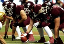 Dynamic shot of American football players in formation on the field, ready to start the game.