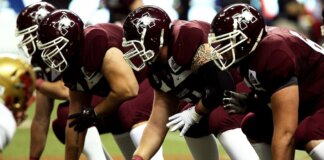 Dynamic shot of American football players in formation on the field, ready to start the game.