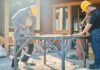 Two construction workers using power tools on a sunny day.