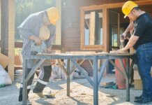 Two construction workers using power tools on a sunny day.