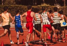 A group of male athletes competing in a track and field event outdoors under a sunny sky.