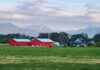 Либералы снова отказались защищать права собственников жилья A serene farm in Agassiz, BC with red barns and mountain backdrop under a blue sky.