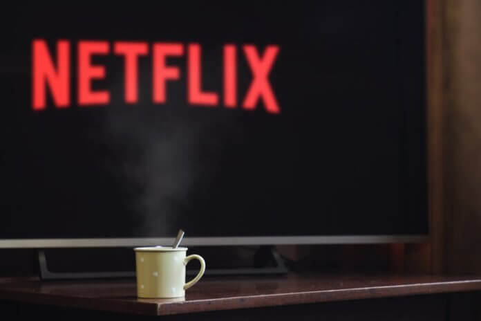 A steaming mug on a table in front of a TV displaying Netflix, creating a cozy indoor atmosphere. A steaming mug on a table in front of a TV displaying Netflix, creating a cozy indoor atmosphere.