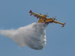 Aerial view of a firefighting plane deploying water over a fire in an emergency response.