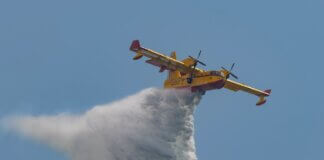 Aerial view of a firefighting plane deploying water over a fire in an emergency response.