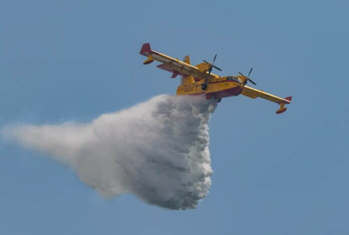 Aerial view of a firefighting plane deploying water over a fire in an emergency response.
