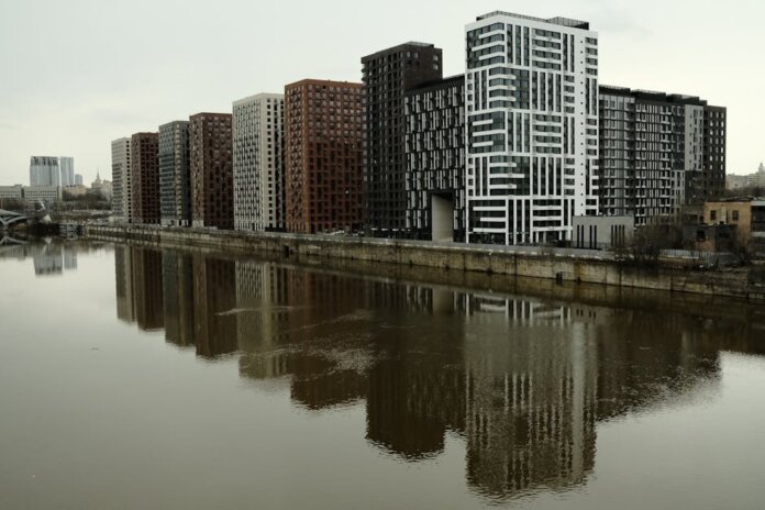 Captivating view of modern high-rise buildings reflecting in a calm river under cloudy skies. Captivating view of modern high-rise buildings reflecting in a calm river under cloudy skies.