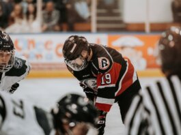 Close-up action scene of ice hockey players in full gear competing on an indoor rink.