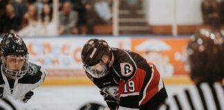 Close-up action scene of ice hockey players in full gear competing on an indoor rink.