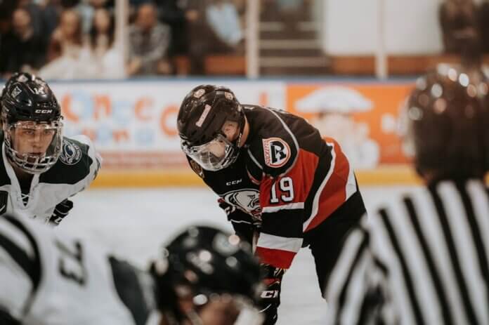 Close-up action scene of ice hockey players in full gear competing on an indoor rink. Close-up action scene of ice hockey players in full gear competing on an indoor rink.