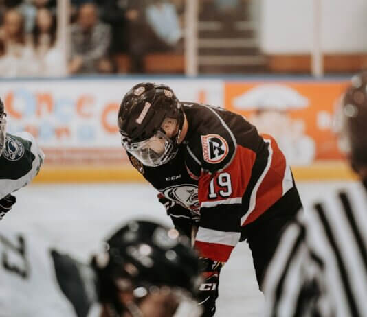 Close-up action scene of ice hockey players in full gear competing on an indoor rink.