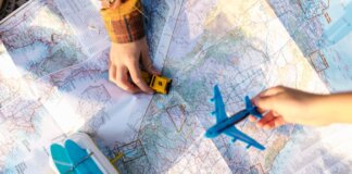 Hands holding a toy airplane and car over a map, symbolizing travel planning and exploration.