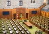 Interior view of the Canadian House of Commons with green seating and wooden decor.
