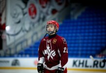 Teen ice hockey player in full gear on an indoor rink, ready for action.