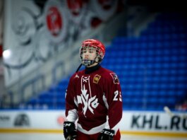 Teen ice hockey player in full gear on an indoor rink, ready for action.