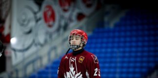 Teen ice hockey player in full gear on an indoor rink, ready for action.