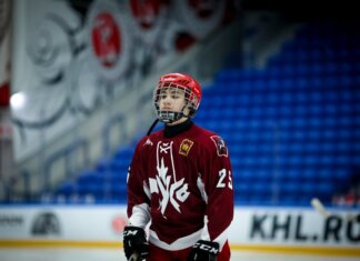 Teen ice hockey player in full gear on an indoor rink, ready for action.