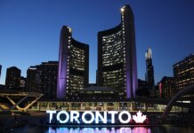 Toronto City Hall stands illuminated against the night sky, showcasing vibrant city lights and iconic architecture.