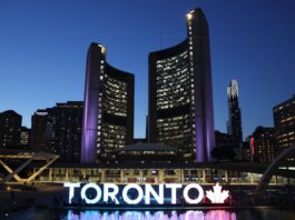 Toronto City Hall stands illuminated against the night sky, showcasing vibrant city lights and iconic architecture.
