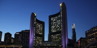 Toronto City Hall stands illuminated against the night sky, showcasing vibrant city lights and iconic architecture.