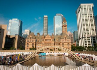 Правительство Канады выделяет средства на фестивали в Нью-Брансуике Toronto's historic Old City Hall and Nathan Phillips Square with reflecting pool under blue sky.