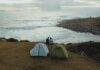 Кемпинг Tribune Bay в Британской Колумбии откроется после реконструкции Two tents and a couple enjoying a scenic coastal view in Palhoça, Brazil.