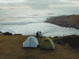Two tents and a couple enjoying a scenic coastal view in Palhoça, Brazil.