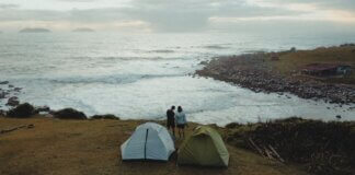 Two tents and a couple enjoying a scenic coastal view in Palhoça, Brazil.