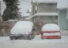 Two snow-covered cars parked on a quiet winter street in Surrey, BC, Canada.