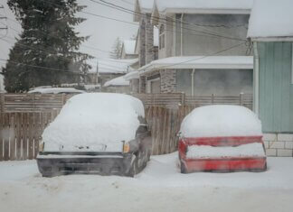 Two snow-covered cars parked on a quiet winter street in Surrey, BC, Canada.