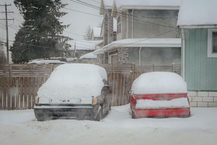 Two snow-covered cars parked on a quiet winter street in Surrey, BC, Canada. Two snow-covered cars parked on a quiet winter street in Surrey, BC, Canada.