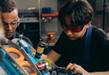 Британская Колумбия инвестирует $40 млн в обучение рабочим профессиям Two young engineers concentrating on precision work in a technical workshop, wearing safety goggles.
