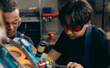 Британская Колумбия инвестирует $40 млн в обучение рабочим профессиям Two young engineers concentrating on precision work in a technical workshop, wearing safety goggles.