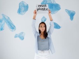 A determined woman holds a sign against plastic pollution amidst floating bags.