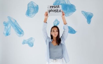 A determined woman holds a sign against plastic pollution amidst floating bags.