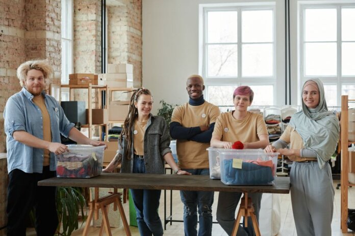 A diverse team of volunteers sorts clothing donations in an organized workspace, promoting community support. A diverse team of volunteers sorts clothing donations in an organized workspace, promoting community support.