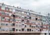 A large urban apartment block featuring a weathered facade with peeling paint and balconies.