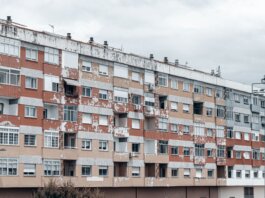 A large urban apartment block featuring a weathered facade with peeling paint and balconies.