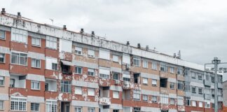 A large urban apartment block featuring a weathered facade with peeling paint and balconies.