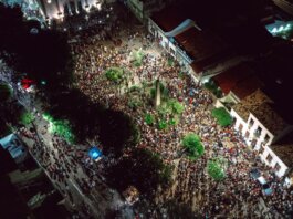 A lively aerial view of a crowded nighttime street festival with illuminated streets.