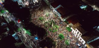 A lively aerial view of a crowded nighttime street festival with illuminated streets.