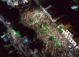 A lively aerial view of a crowded nighttime street festival with illuminated streets.