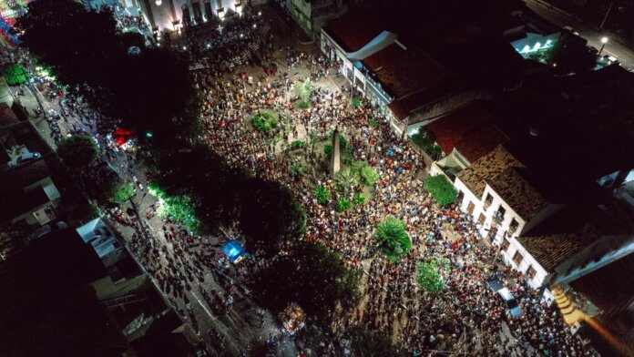 A lively aerial view of a crowded nighttime street festival with illuminated streets.