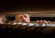 A man searches through archives in an office storage room, focused and working.