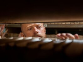 A man searches through archives in an office storage room, focused and working.