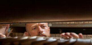 A man searches through archives in an office storage room, focused and working.