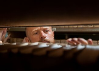 A man searches through archives in an office storage room, focused and working.